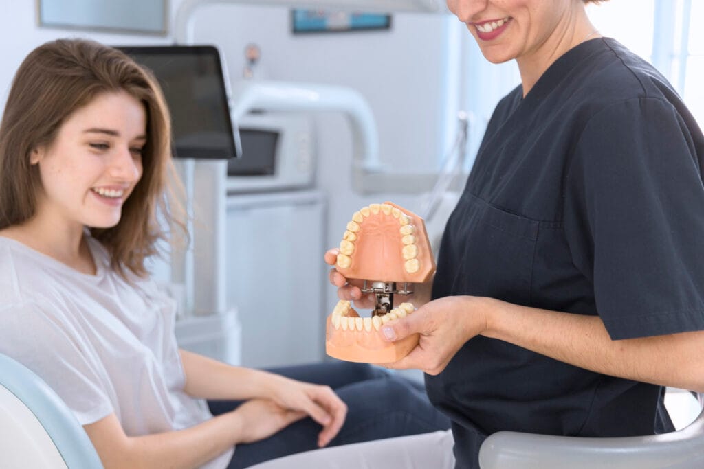 close up dentist showing teeth model smiling patient